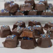 A white surface with chocolate caramel pieces placed all over it.