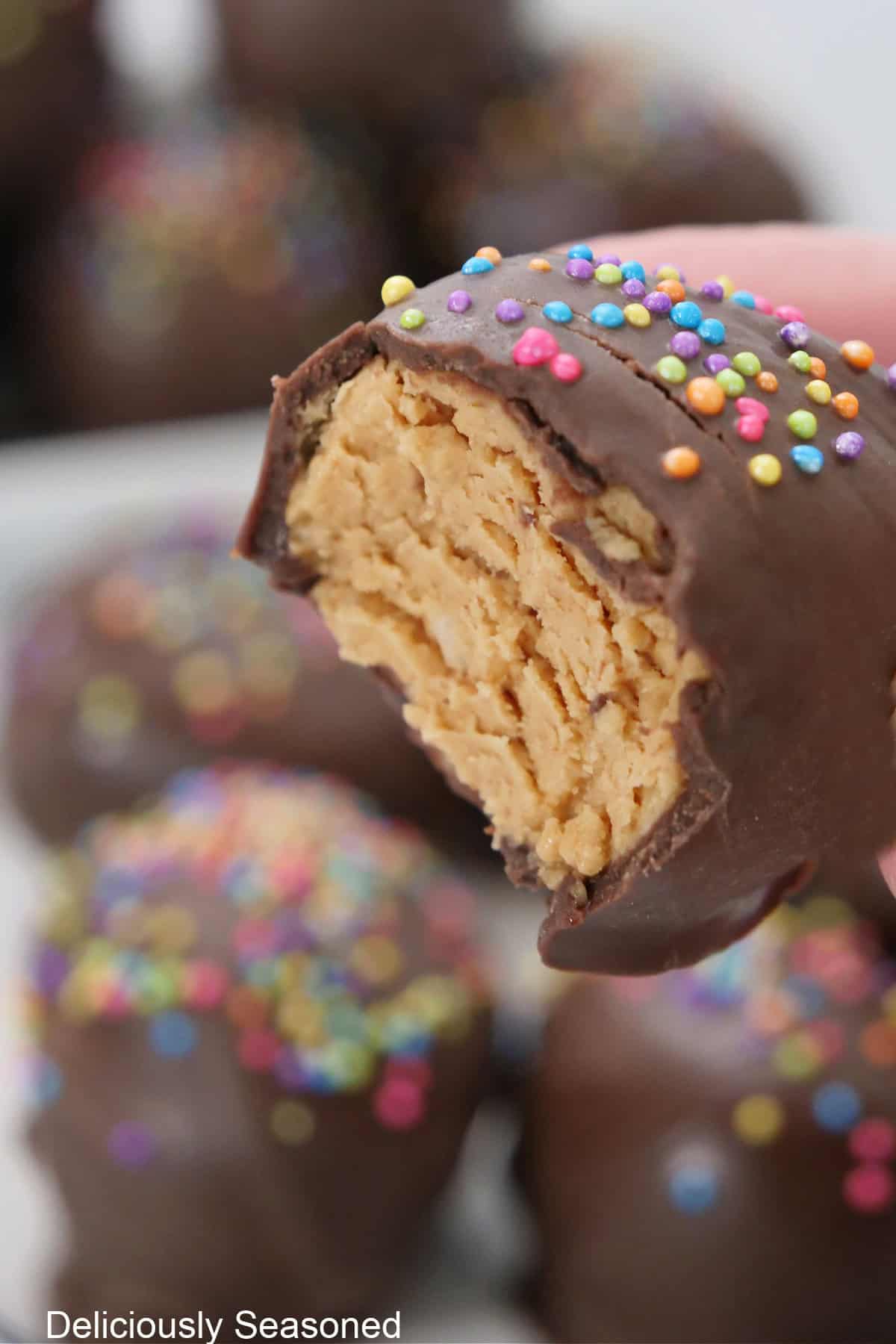 A cookie butter mini Easter egg held up with a bite taken out of it showing the center of the candy egg.
