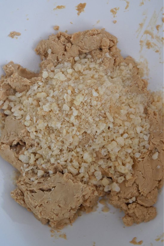 A mixing bowl with the cookie butter dough and crushed rice krispies in it.