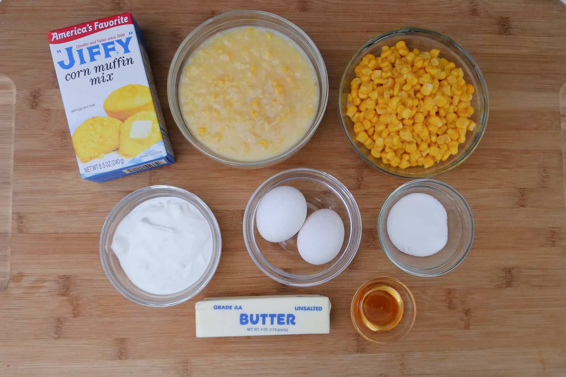 A wood surface with the ingredients place on it to make cornbread souffle.