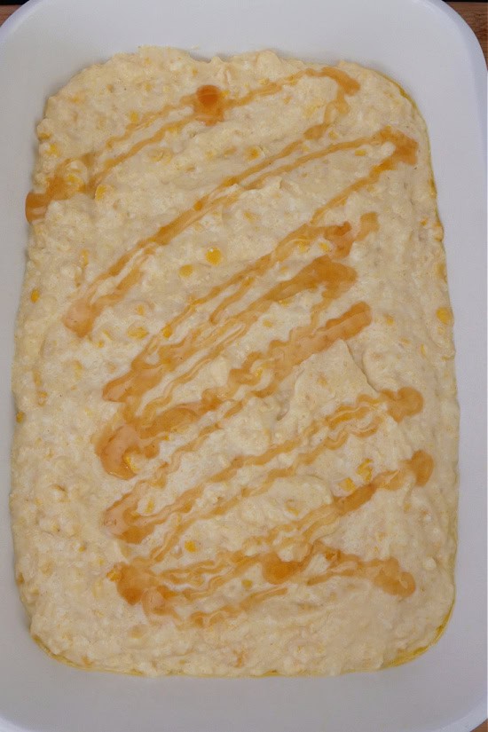A white 9x13 baking dish with cornbread souffle in it before being baked.