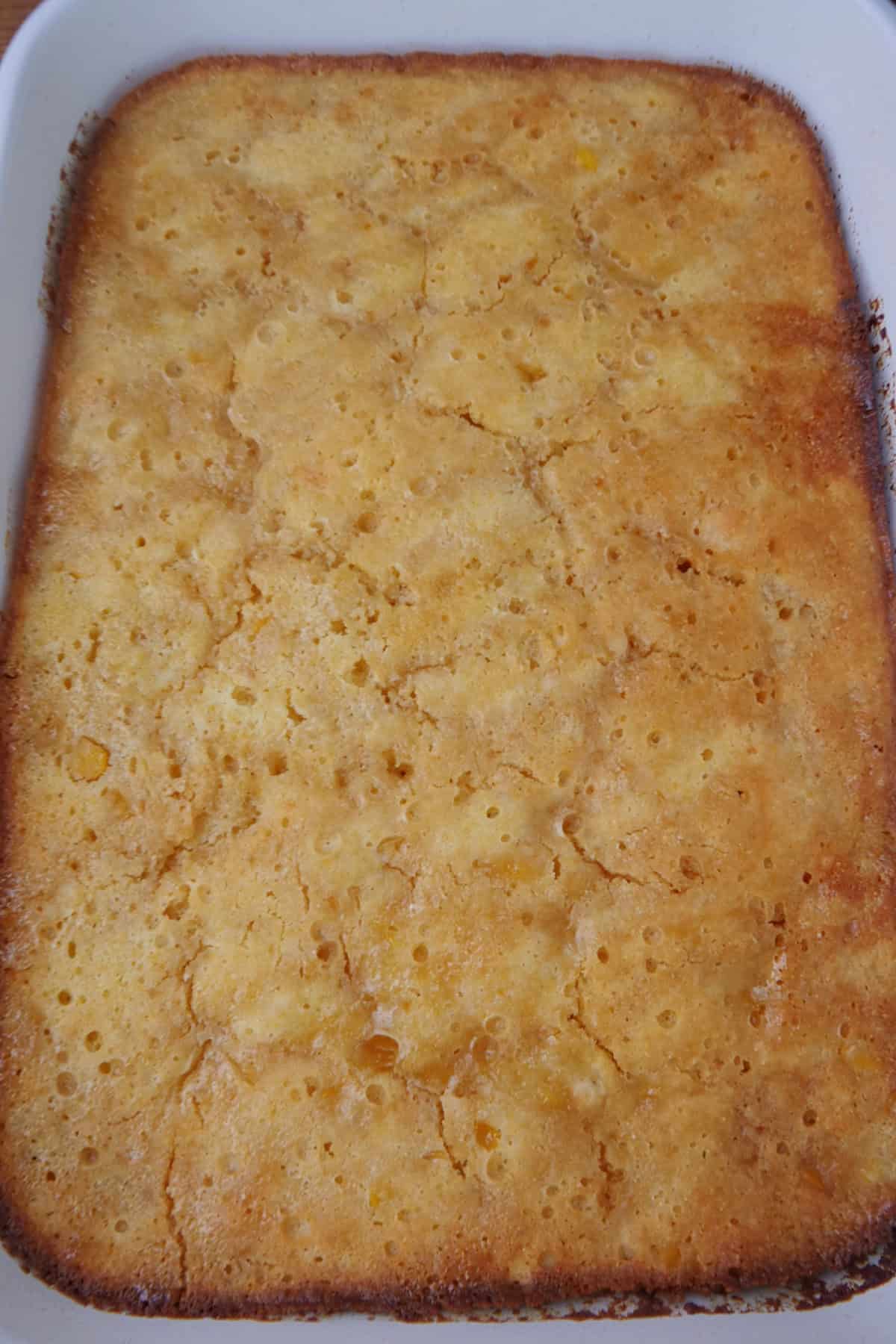 A white baking dish with a baked cornbread souffle in it after being baked.