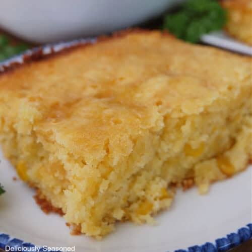 A serving of cornbread souffle on a round white plate with blue trim.