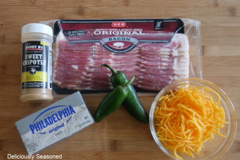 A wood surface with the 5 ingredients needed to make jalapeno popper smoked cream cheese.