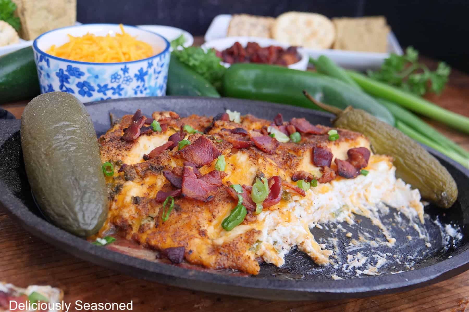 A small black oval cast iron skillet with smoked jalapeno popper cream cheese in it with some removed showing the inside of the cream cheese mixture.