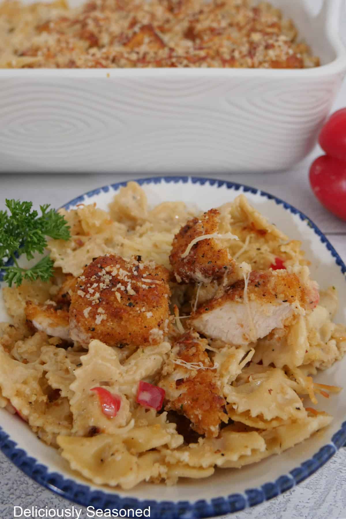 A round white bowl with blue trim with a serving of Parmesan crusted chicken casserole in it.