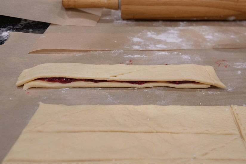 Crescent dough strips with raspberry filling between two strips.