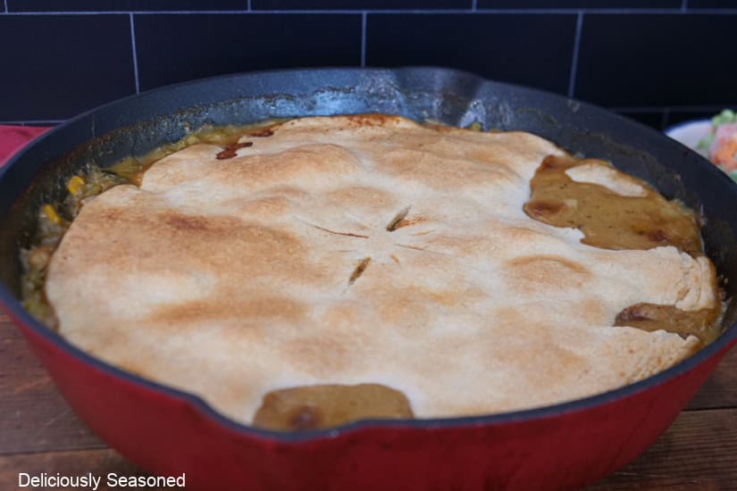 A red cast-iron pan with a baked salsa verde chicken pot pie in it.