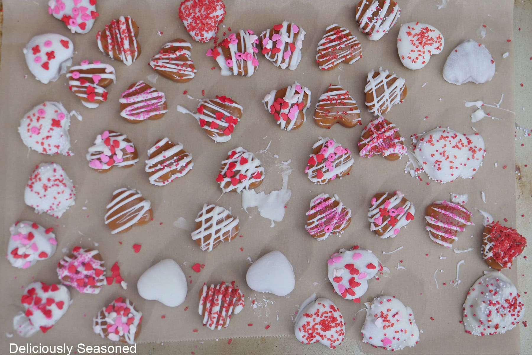 A parchment paper lined baking sheet with decorated caramel hearts on it