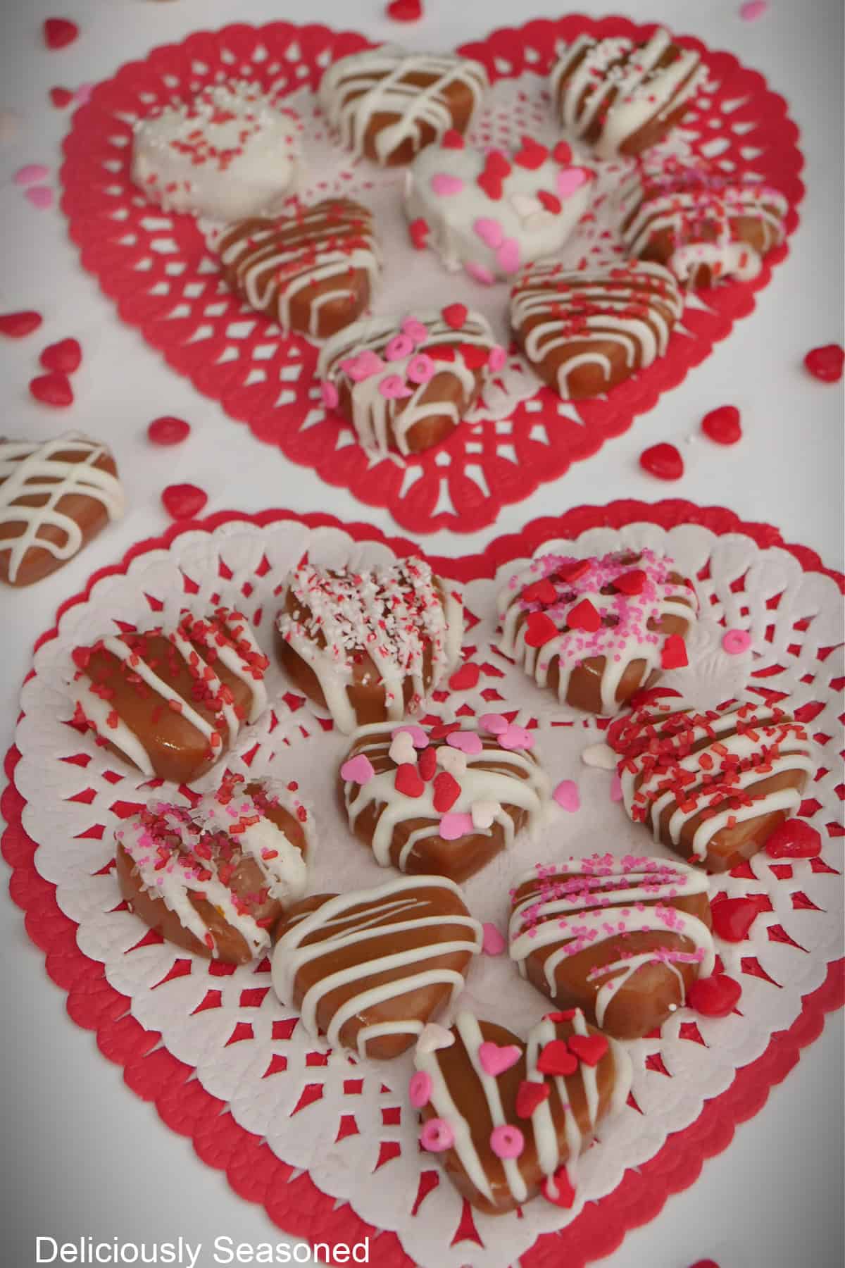 A white surface with red and white heart shaped dollies with heart caramels on it.