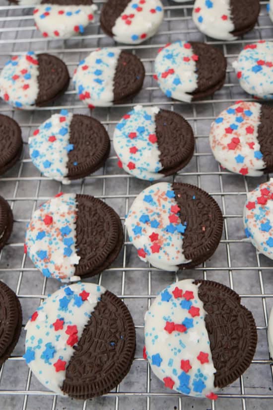 A wire rack with half dipped and decorated Oreo cookies.