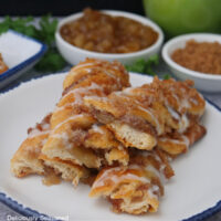 A white round plate with blue trim with a few apple streusel twists on it.