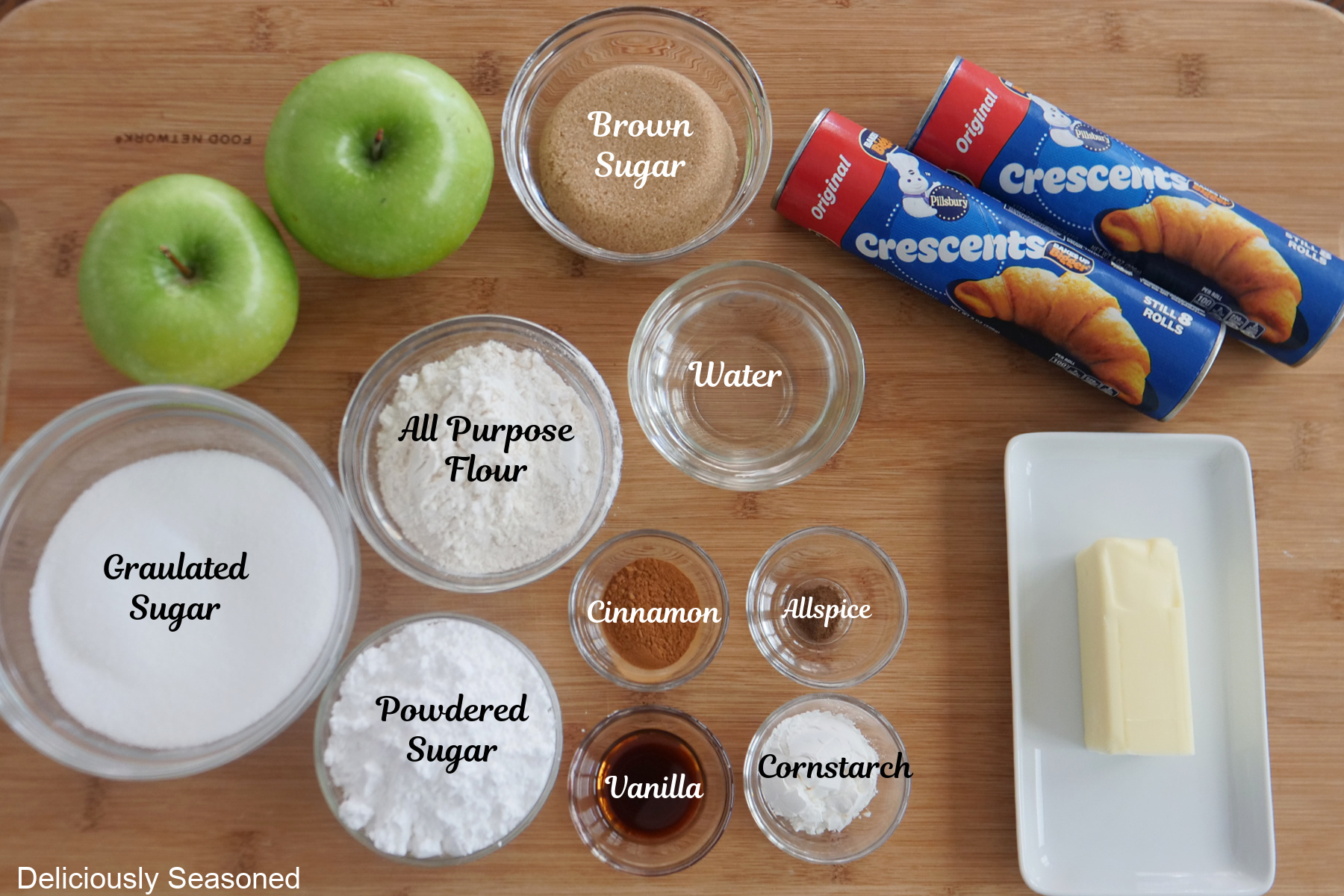 A wood surface with all the ingredients needed to make apple streusel twists placed on it.