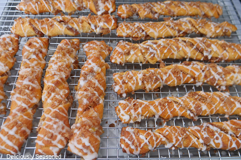 A wire rack with baked apple streusel twists on it that have been drizzled with glaze.