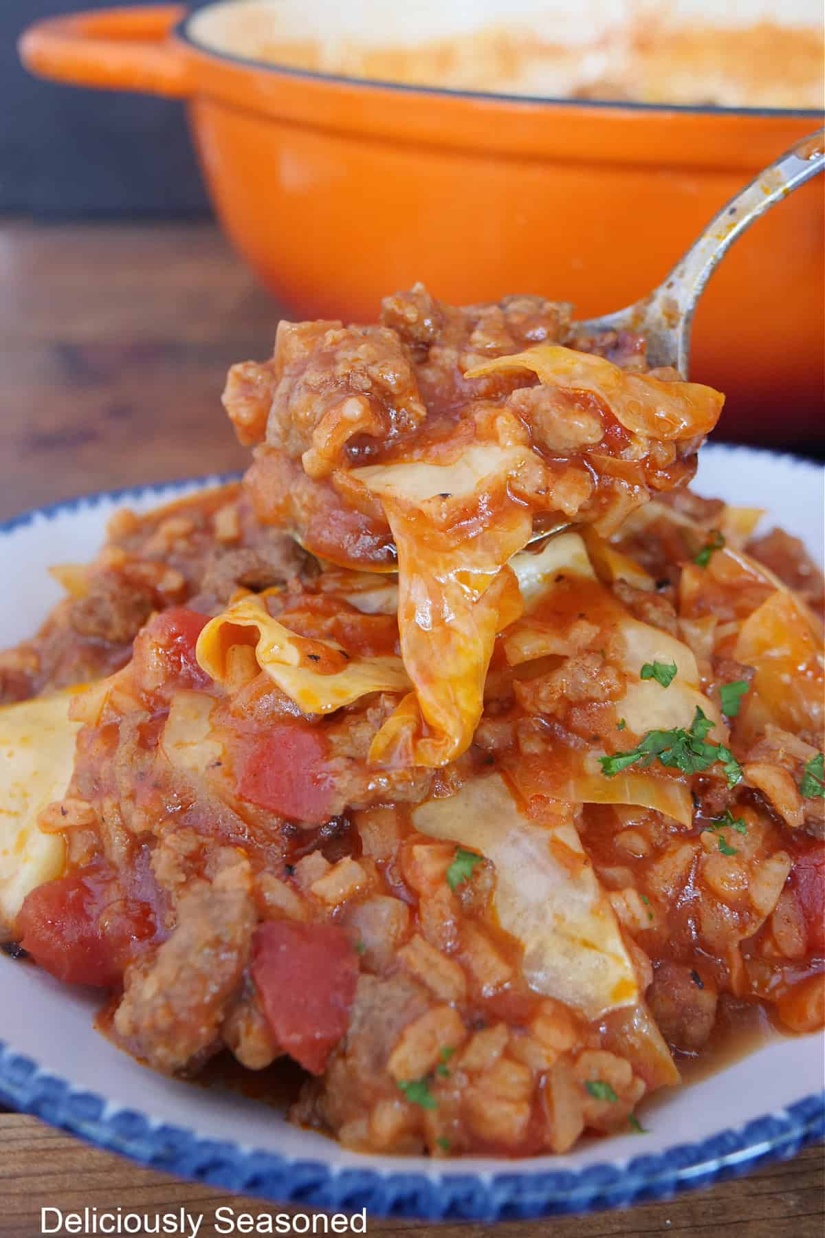 A bite of unstuffed cabbage roll soup on a soup held above a serving of this one-pot meal.