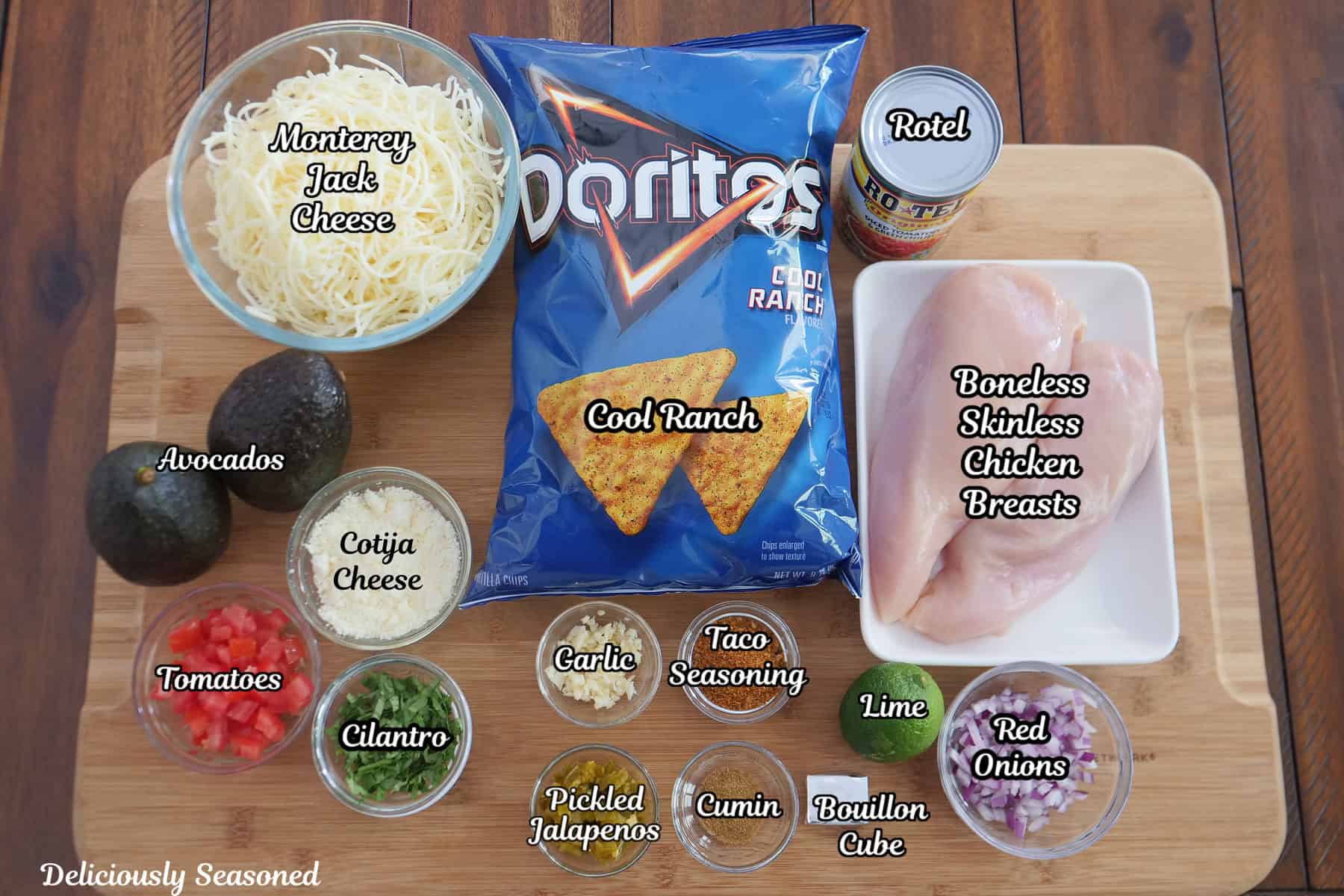 A wood cutting board with all the ingredients to make crunchy Doritos chicken tacos placed on it.