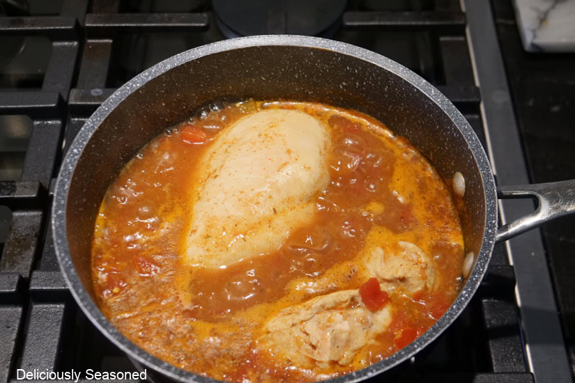 A saucepan with the ingredients for shredded chicken in it.