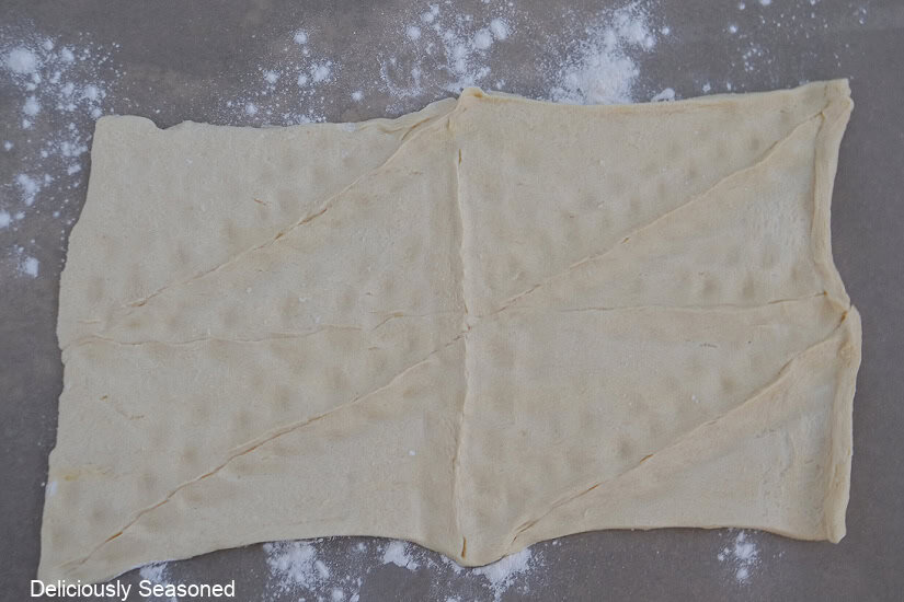 A crescent roll rolled out on the counter with all the seams pinched together.