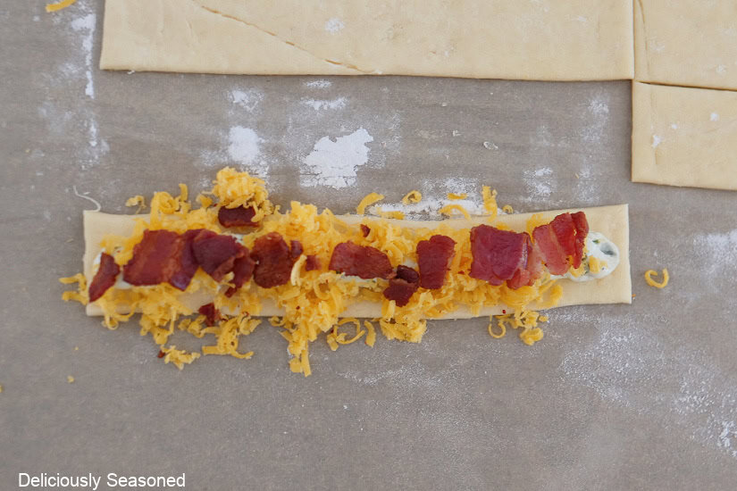 A crescent dough strip with shredded cheese, jalapeno popper mix, and crispy bacon on top.