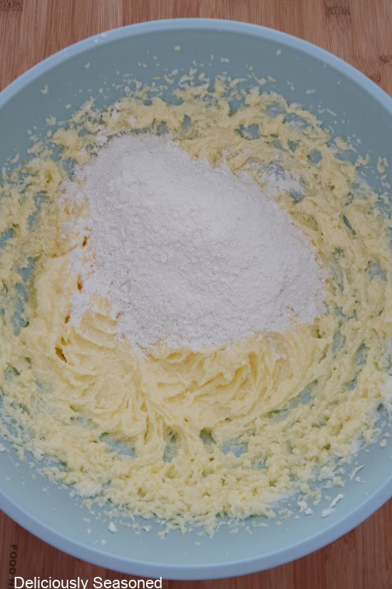 A light blue bowl with the wet batter ingredients in it with the flour mixture being added.