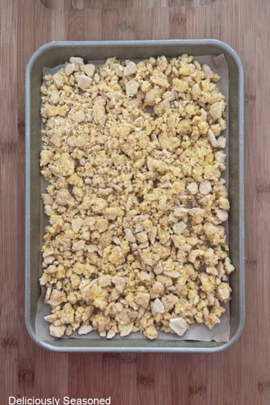 A baking sheet with lemon crunch mix spread out in an even layer before being baked.
