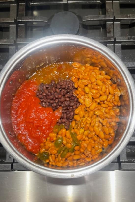 A silver pot with all of the ingredients added to the pot.