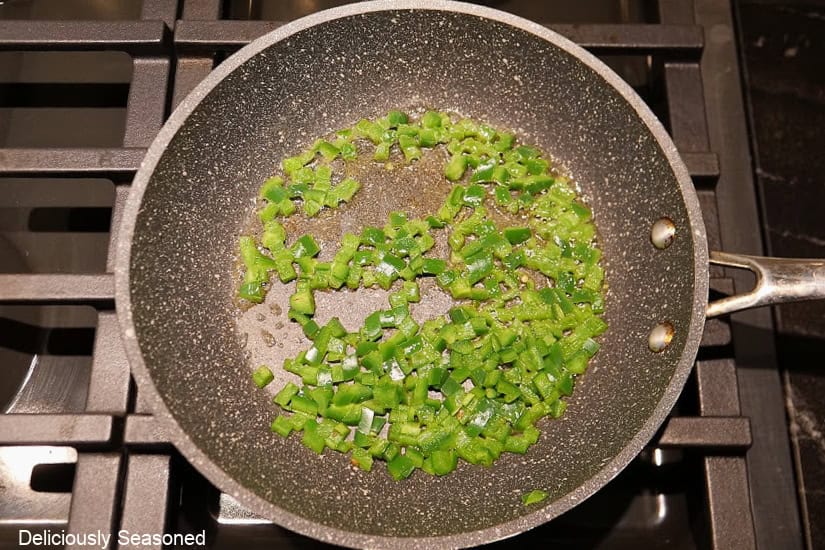 A frying pan with sauteed diced jalapenos in it.