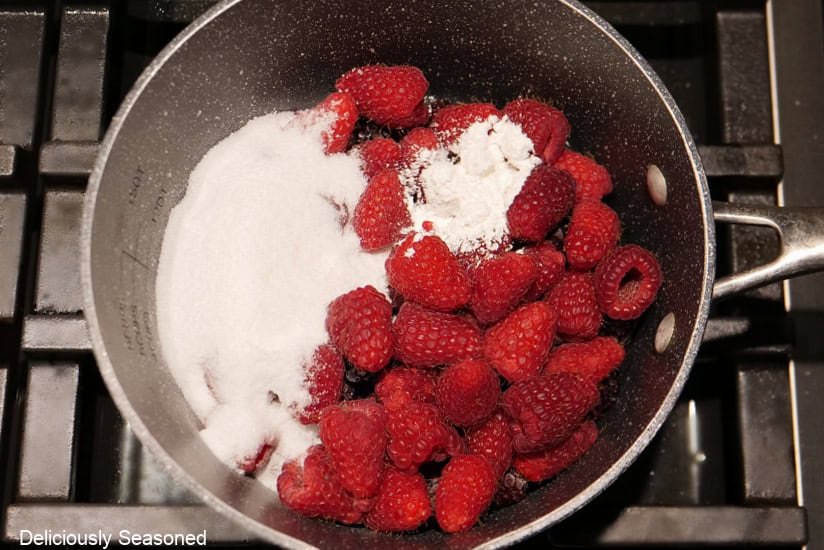 A saucepan with raspberries sugar, lemon juice, and cornstarch in it.