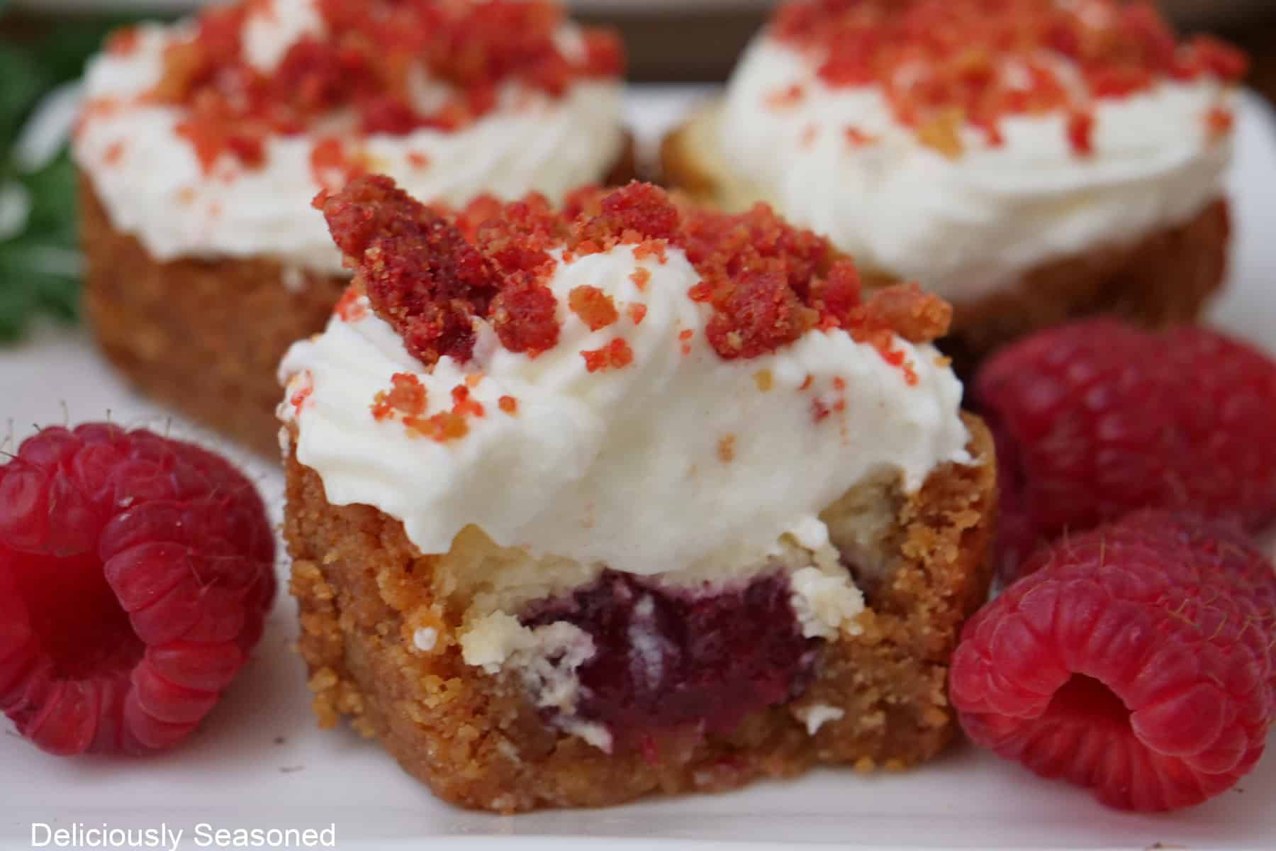 A white plate with mini raspberry crunch cheesecake bites on it.
