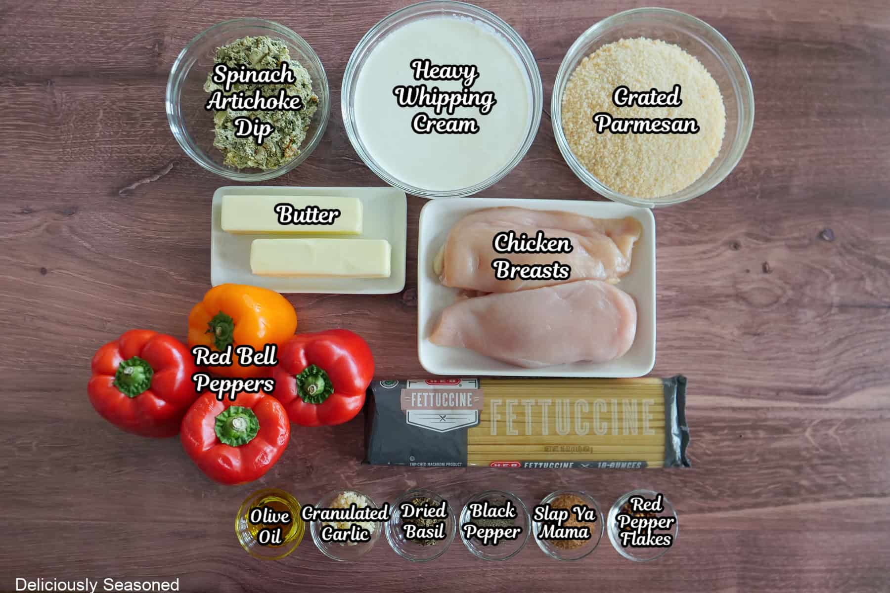 A wood surface with all the ingredients placed on it to make spinach artichoke stuffed chicken with fettuccine pasta.