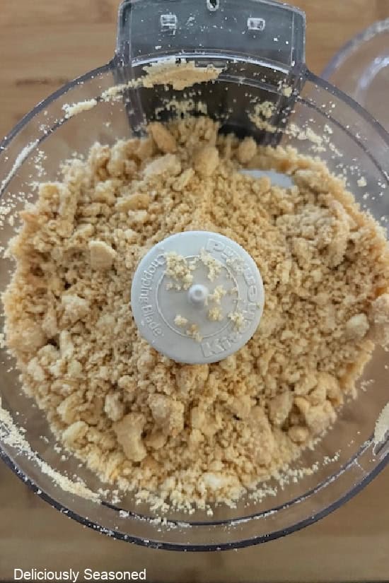 A small food chopper with golden Oreos in it that are crumbled up.