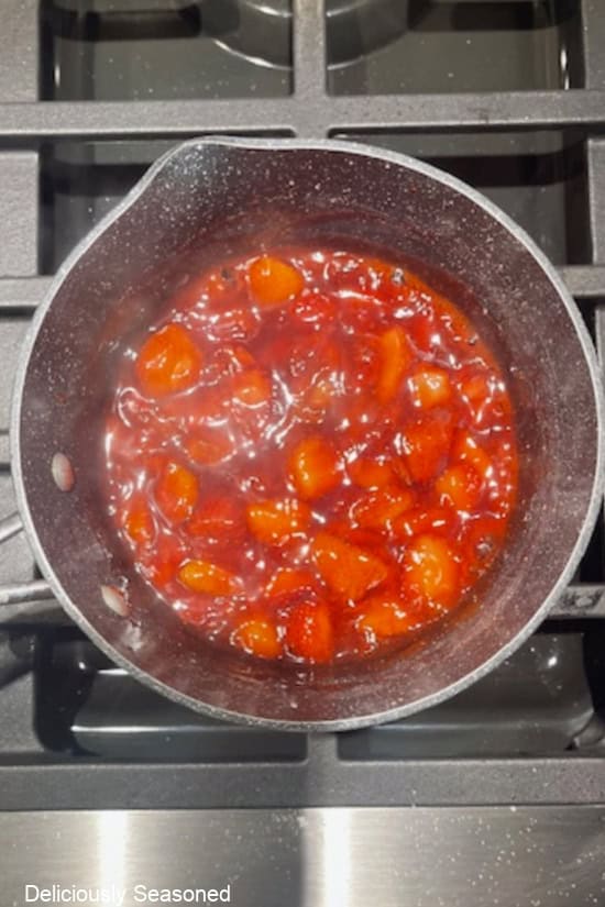 A pan with strawberries boiling in it for the strawberry topping.