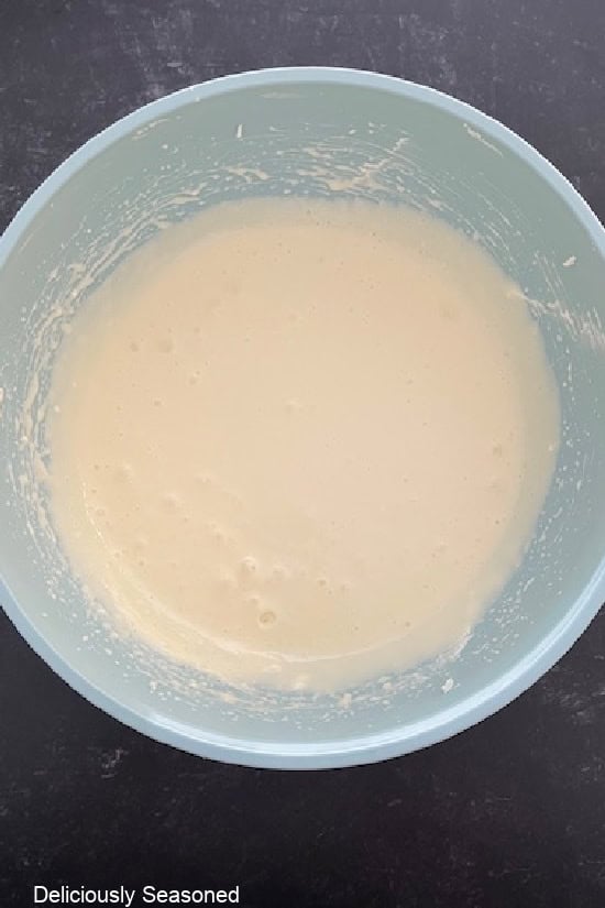 A light blue bowl with the cheesecake batter in it.