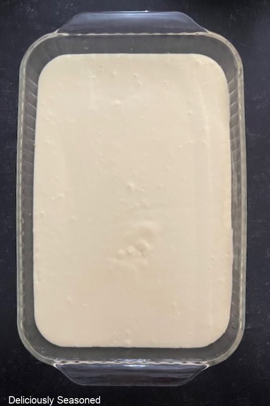 A glass 9x13 baking dish with the cheesecake batter poured over the graham cracker crust.