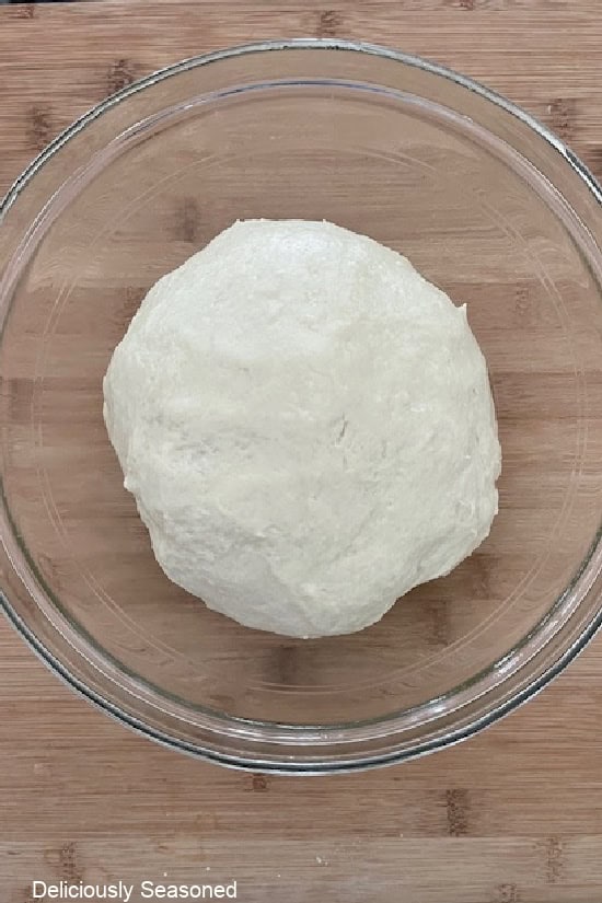 A glass bowl that has been oiled and the homemade sweet roll dough in it.