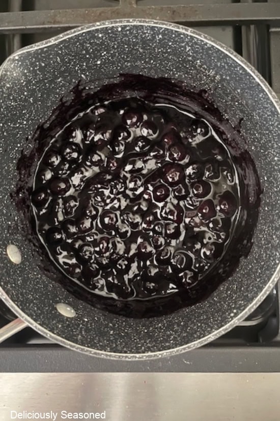 A saucepan on the stovetop with blueberry filling in it.