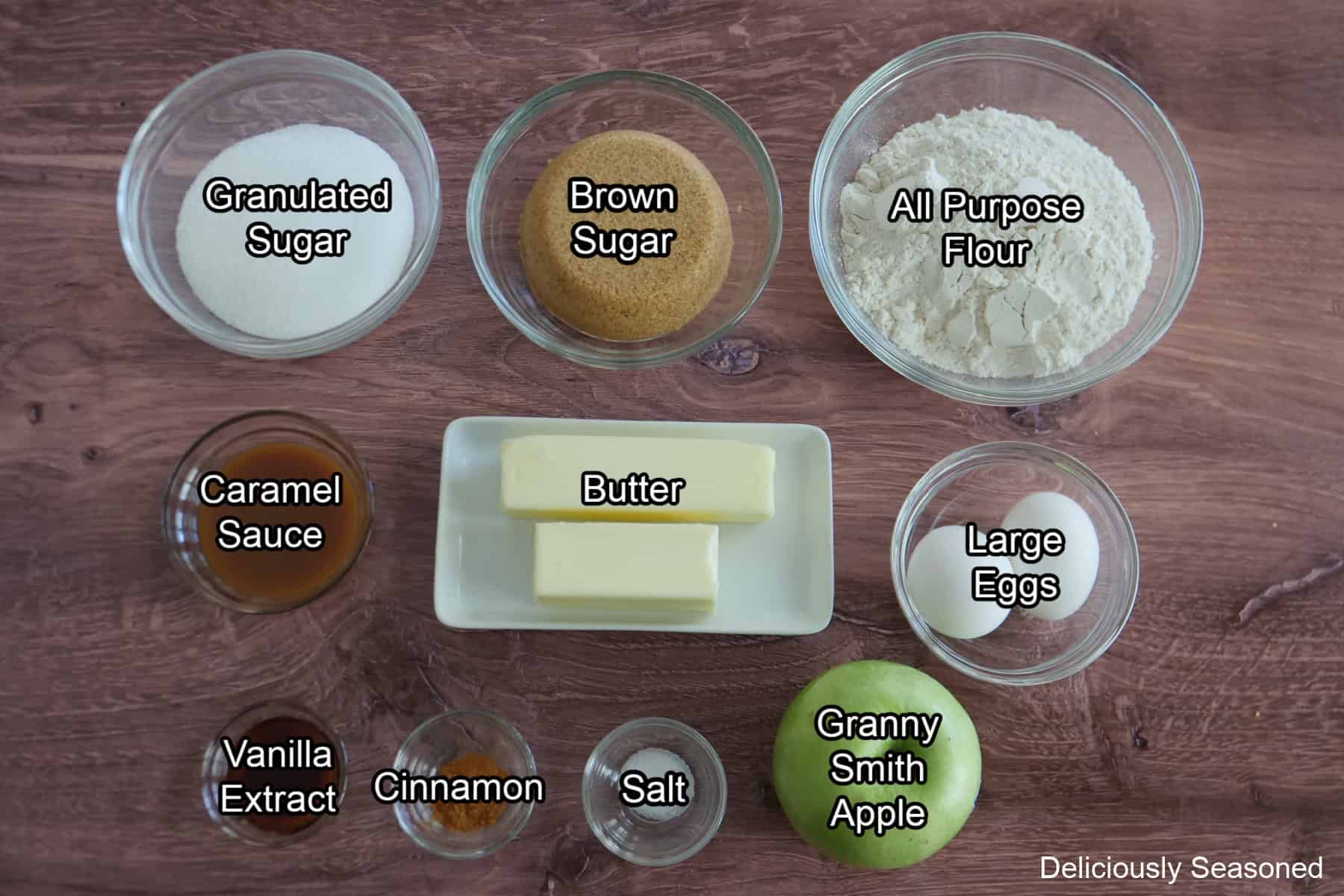 A wood surface with all the ingredients placed on it to make caramel apple blondies.