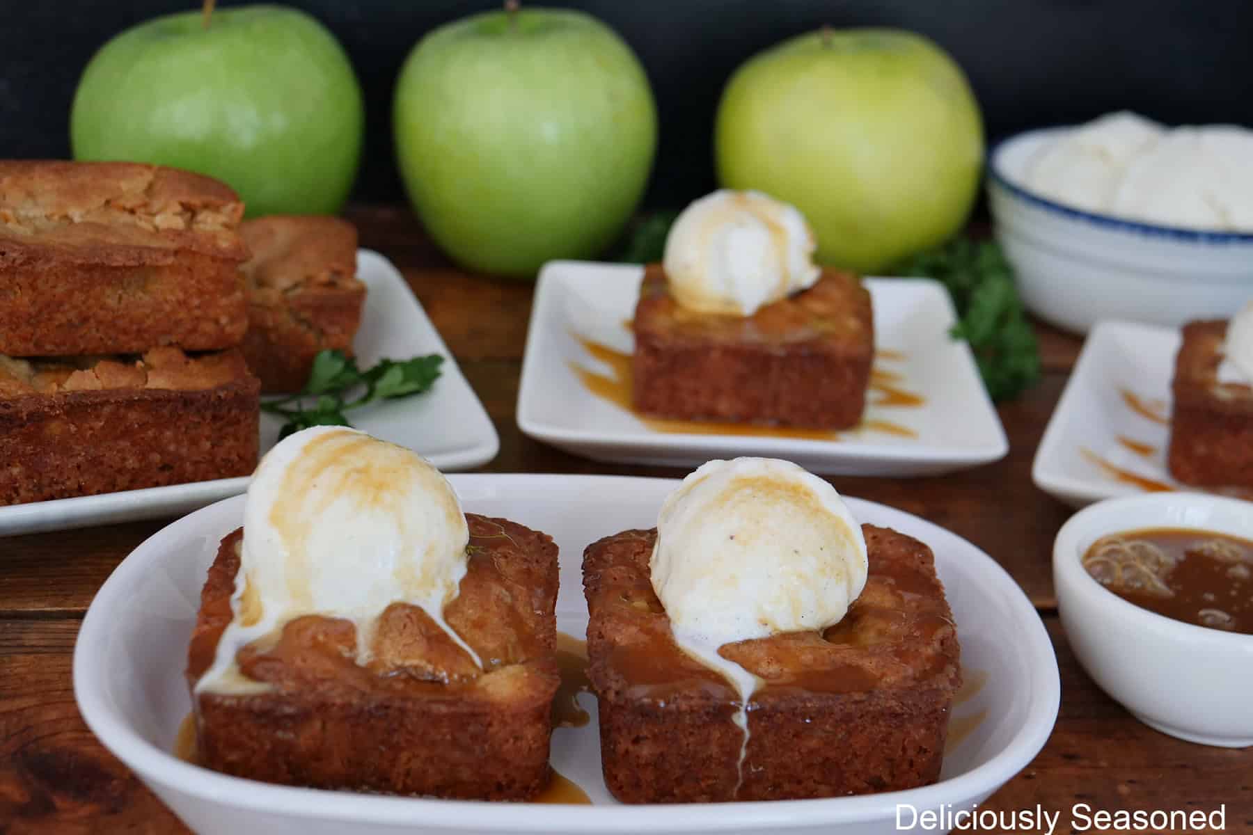 A wood surface with four white plate all with caramel apple blondies on them.