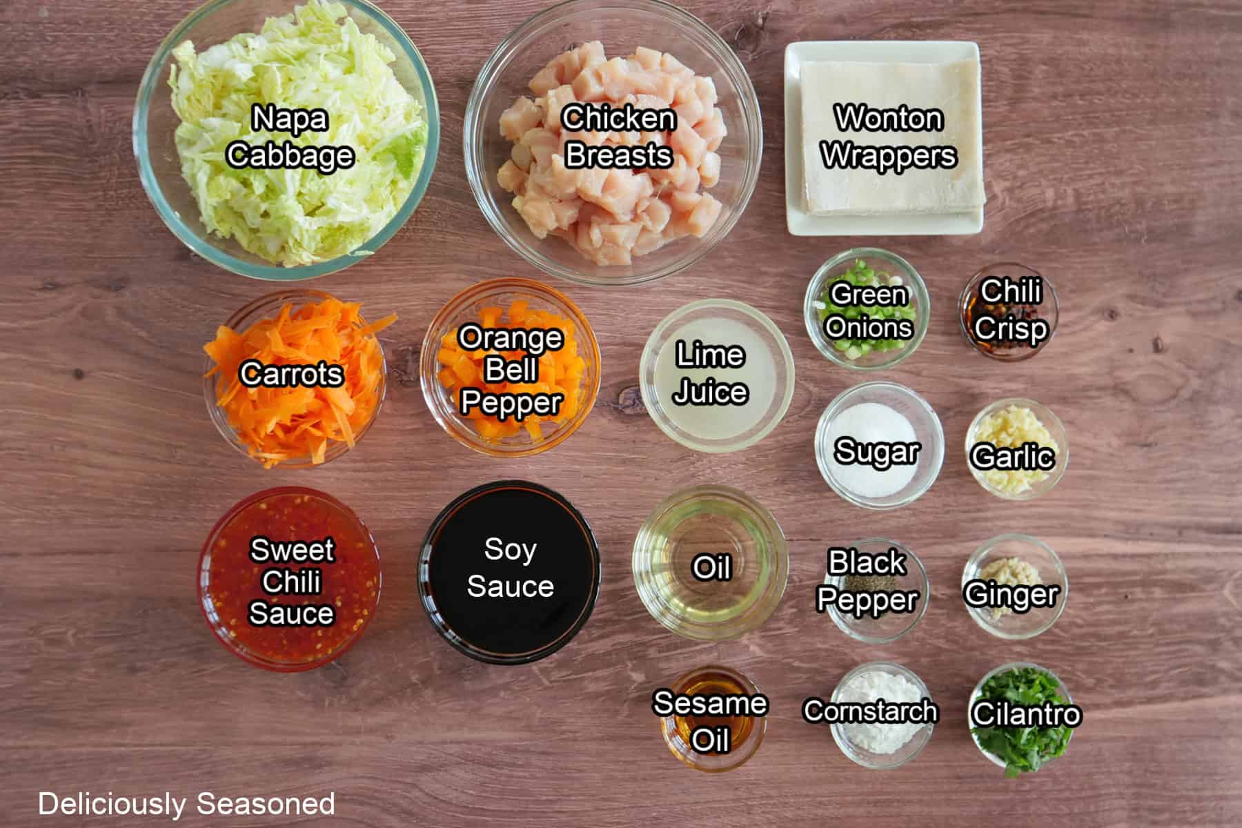 A wood surface with all the ingredients placed in glass bowls to make chicken wonton bowls.