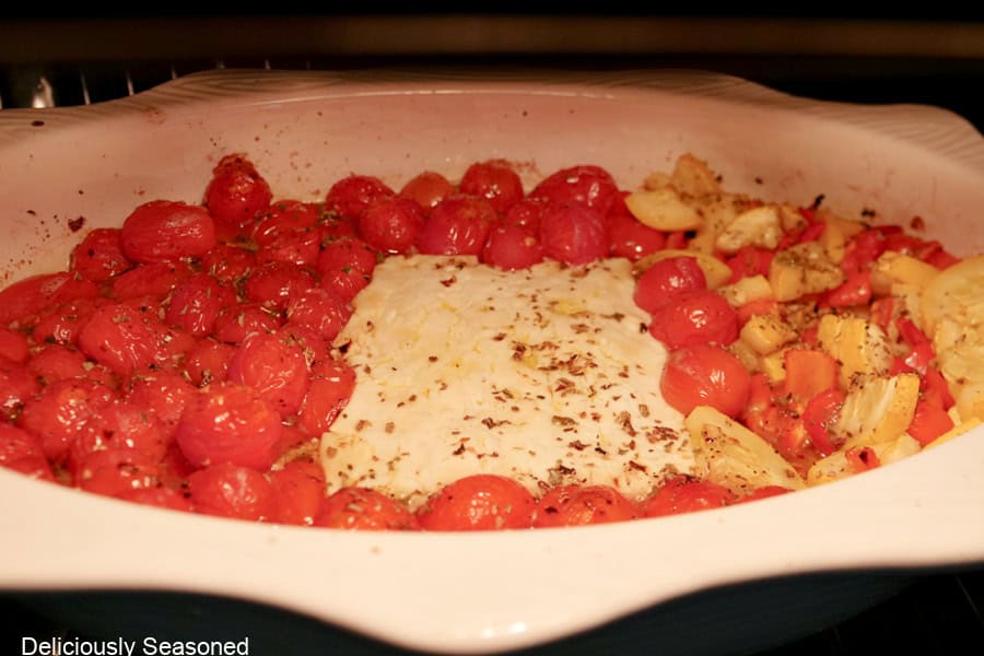 An oval white baking dish in the oven baking the feta tomato squash mixture.