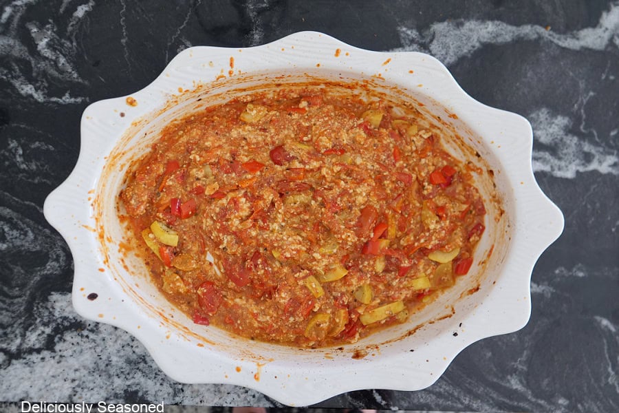 An oval white baking dish after all the feta cheese, tomatoes, and squash are cooked, and it is all mixed together.