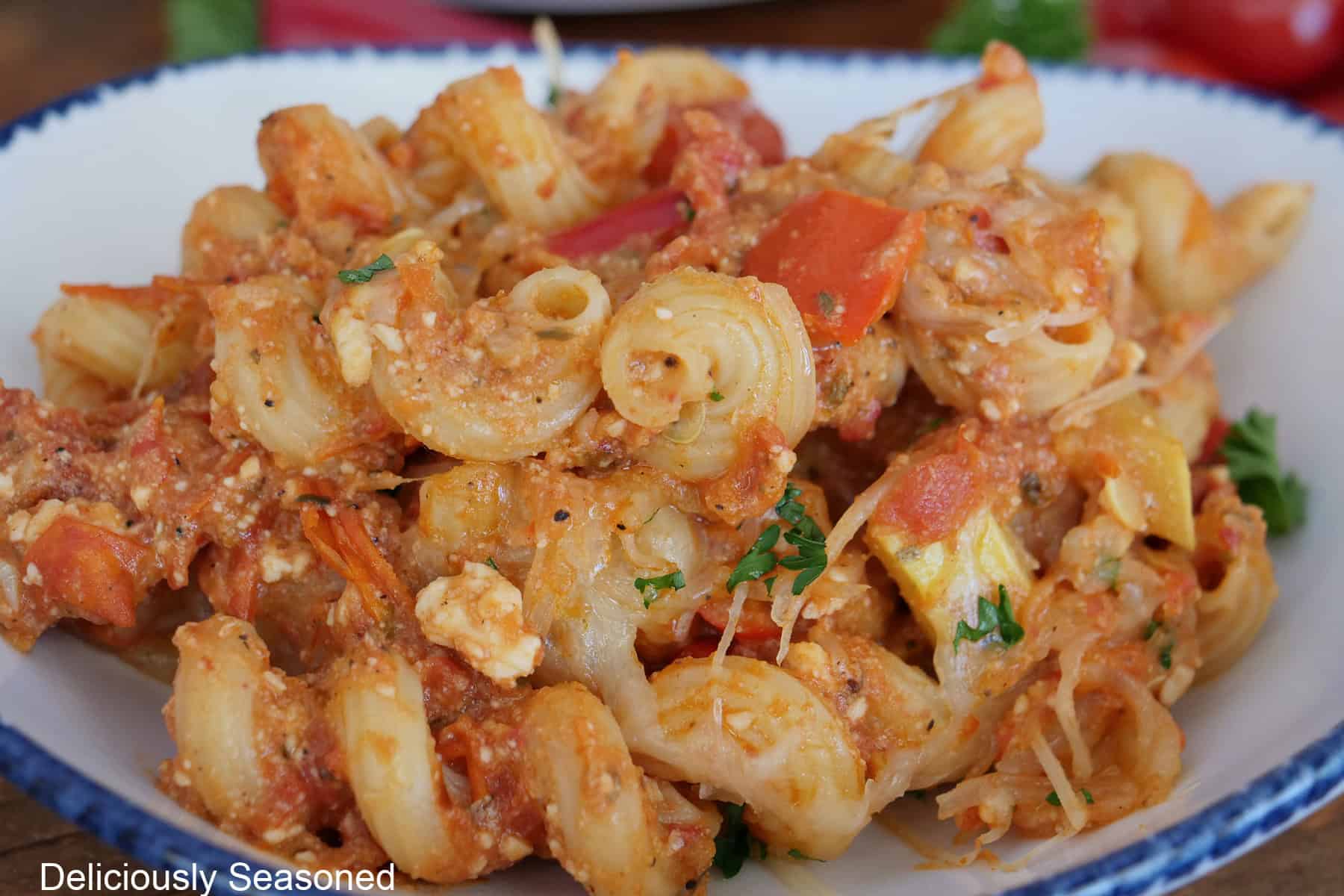 A serving of feta tomato pasta in a white bowl with blue trim.