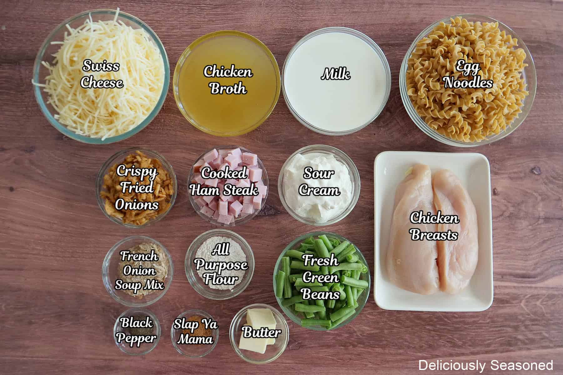 A wood surface with all the ingredients placed on it to make French onion chicken green bean casserole.