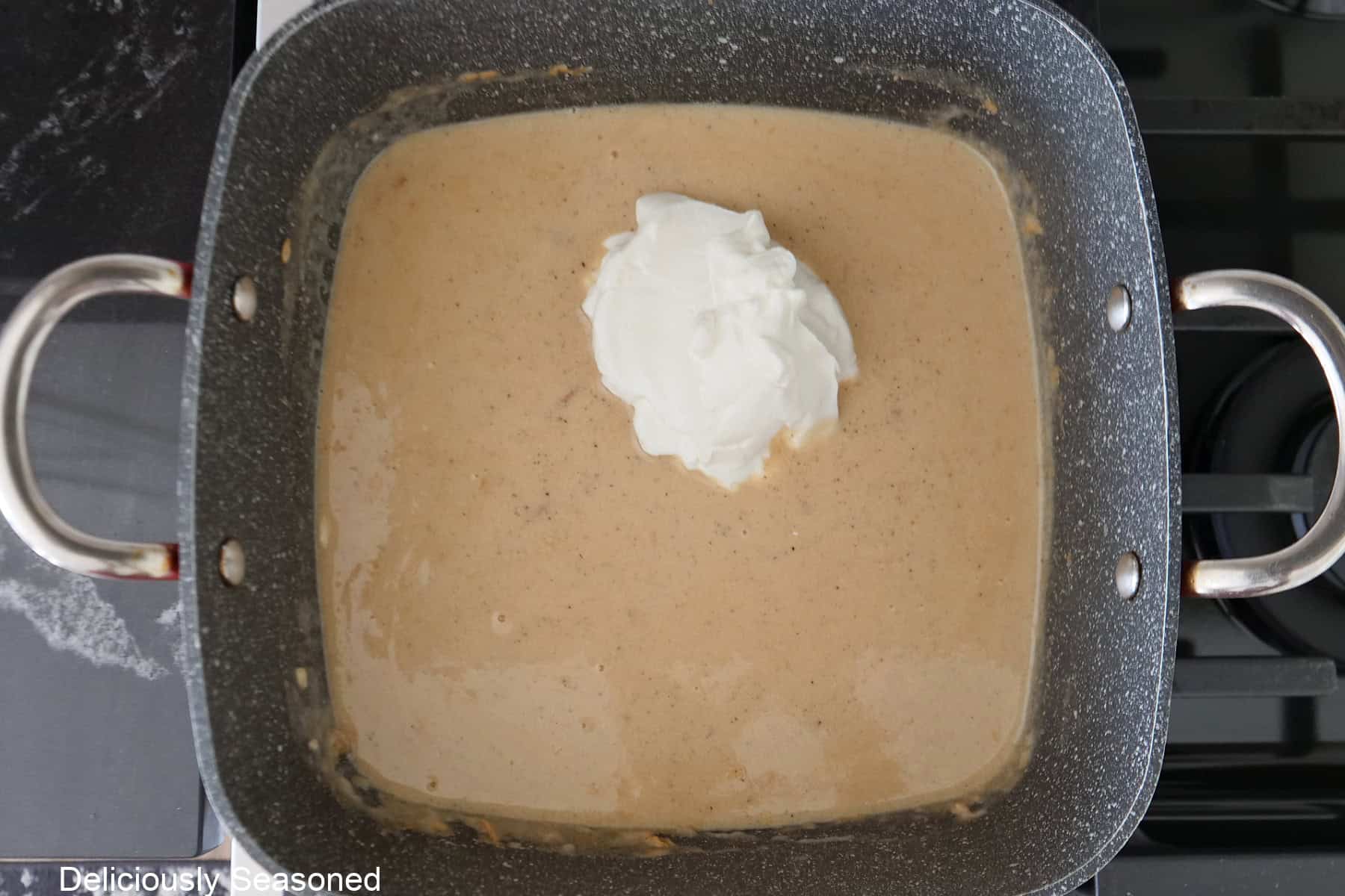A square pot with the creamy sauce in it with sour cream added.