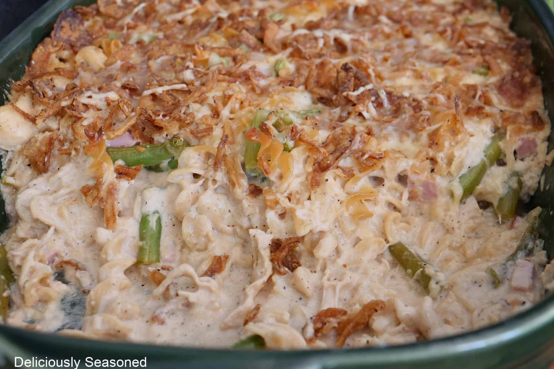 A green baking dish with chicken green bean casserole in it with some removed showing all the creamy and hearty goodness.