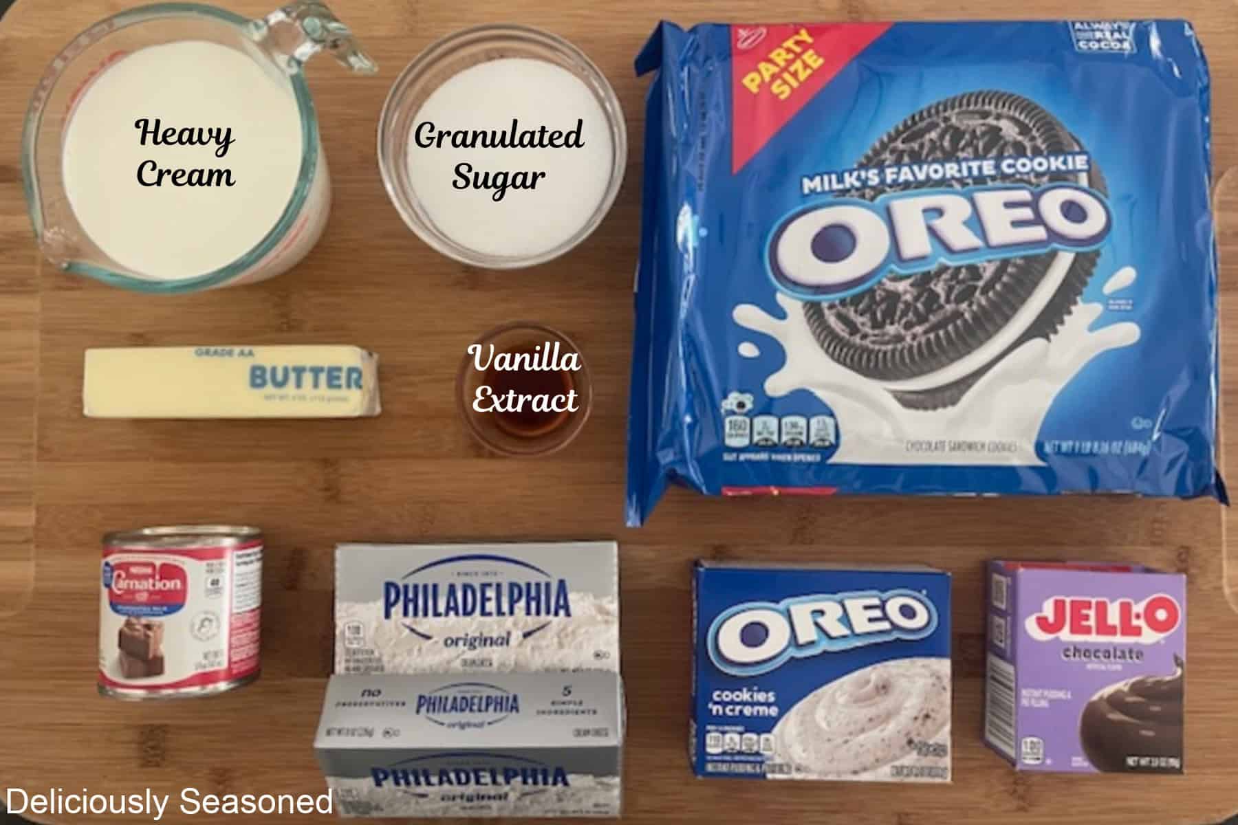 A wood surface with all the ingredients labeled to make Oreo Cream Cheese Pie placed on it.