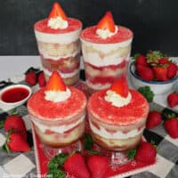 Four strawberry tiramisu parfaits on a black and white, and red surface.
