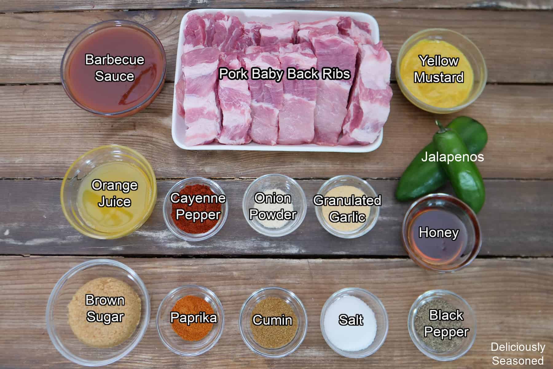 A wood surface with all the ingredients placed on it to make sweet and spicy smoked ribs.