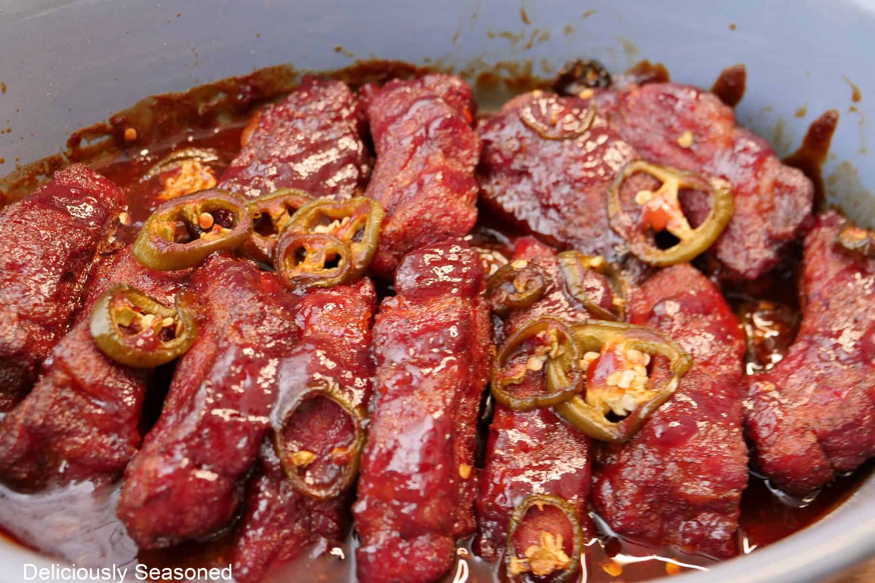 A blue oval baking dish with the smoked sweet and spicy pork ribs in it.