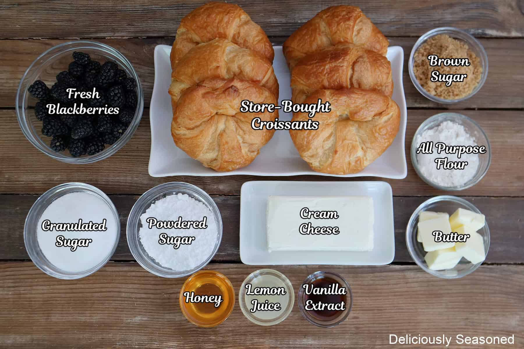 A wood surface with all the ingredients placed on it to make blackberry cream cheese croissants.